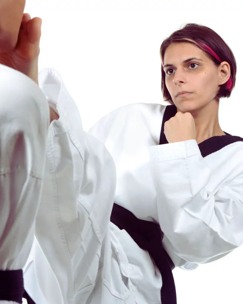 a woman in a karate uniform performing martial arts for people over 50