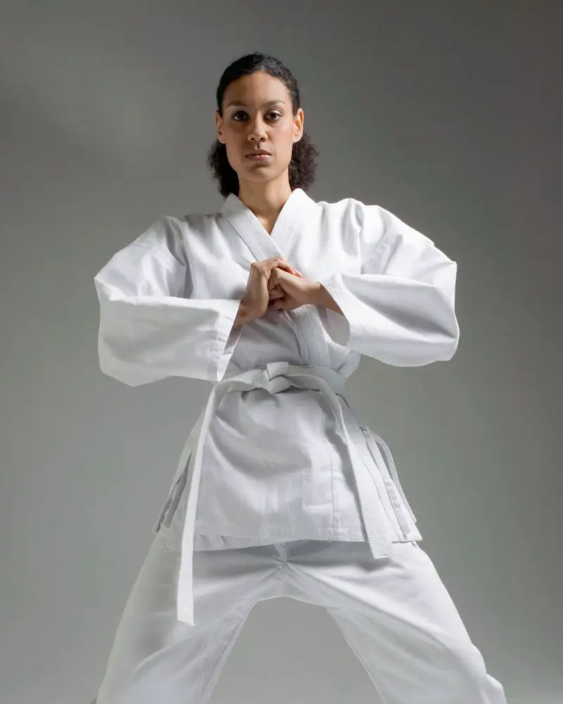 a woman in a white uniform performing martial arts for people over 50