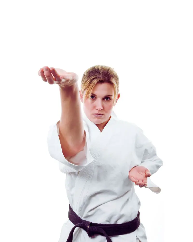 a woman in a white uniform performing martial arts for people over 50