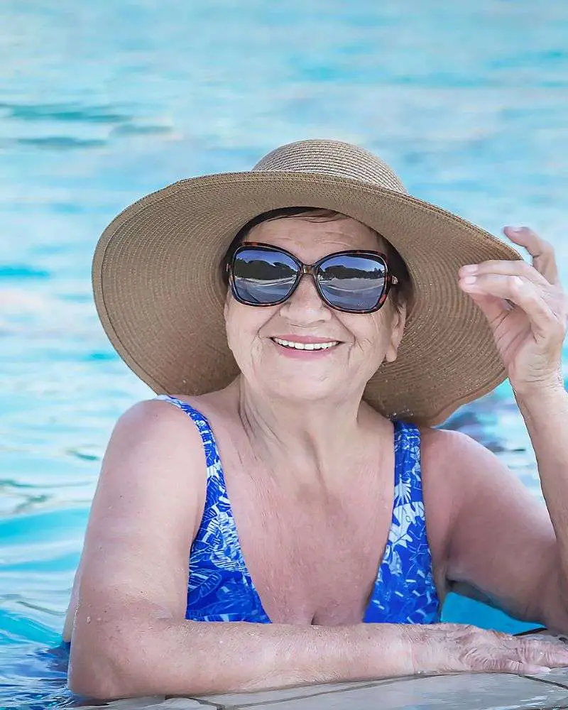 a woman in a swimsuit and hat in a pool enjoying one of many over 50 singles resorts