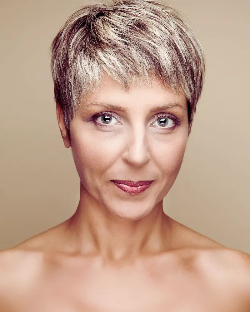 a woman with short pixie cut smiling after discovering the best short haircuts for women over 60