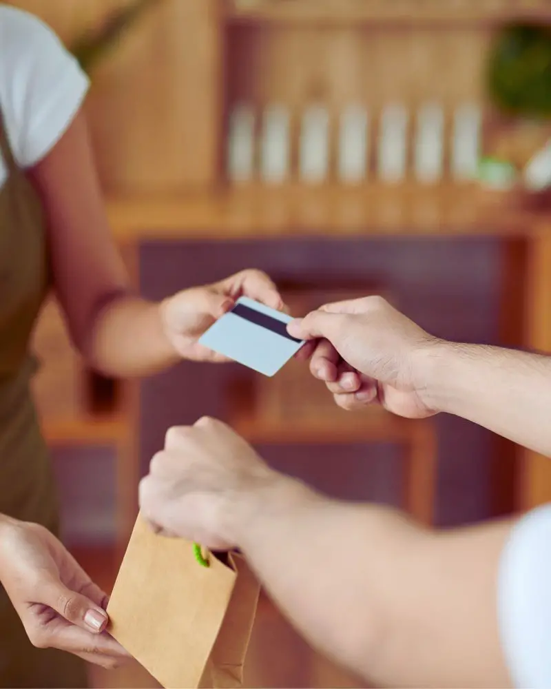 a person handing over a card to a man selling handmade soap