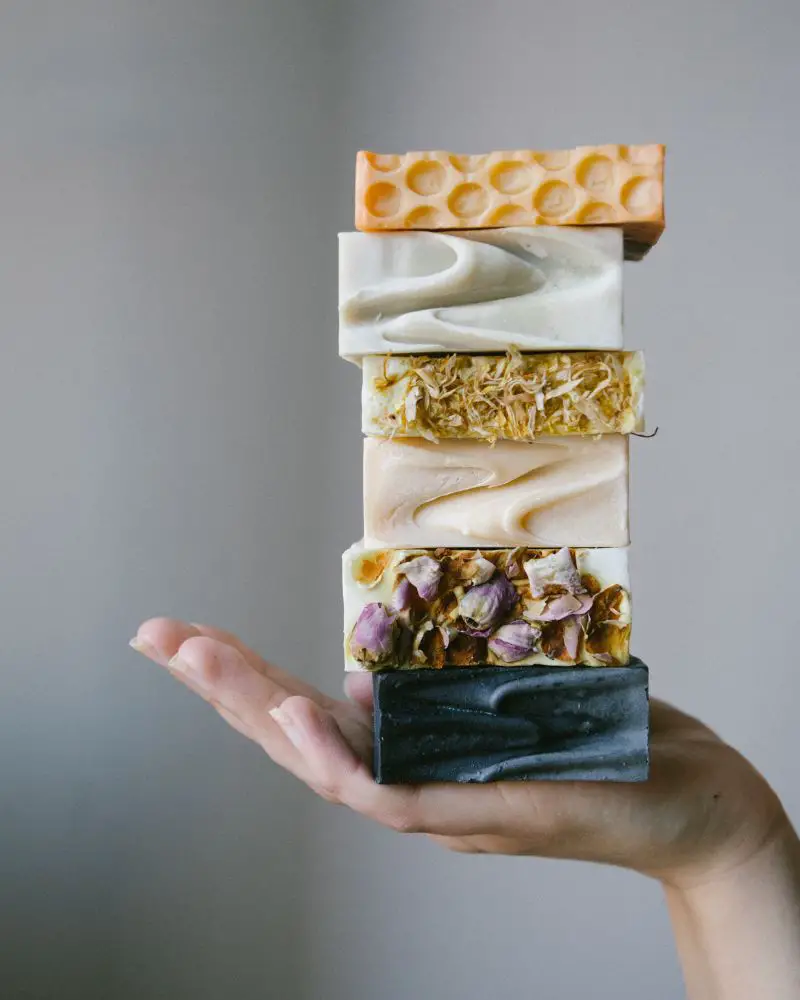 a hand holding a stack of soap as an intro opening to selling handmade soap regulations