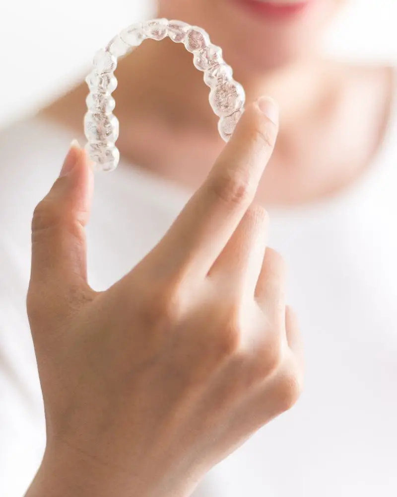 a hand holding a clear plastic retainer