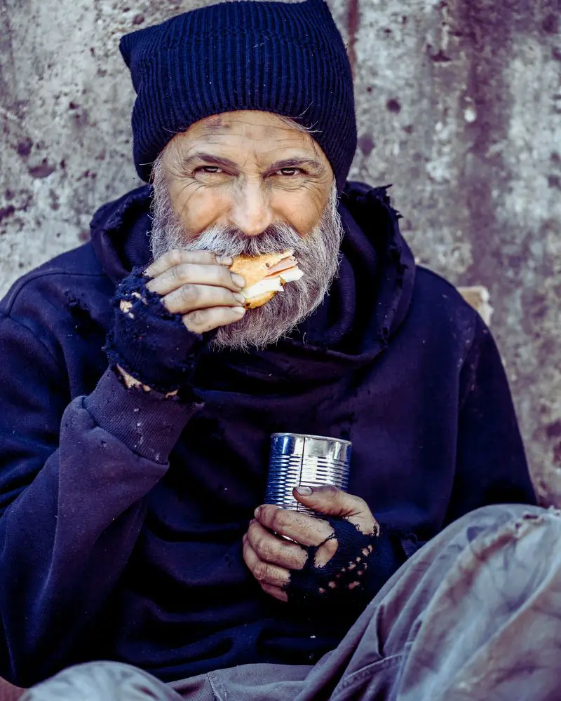 a man eating a sandwich and holding a can