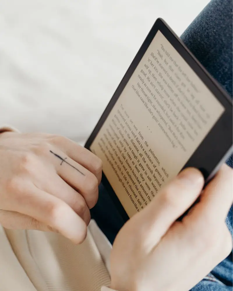 a person holding a tablet reading an ebook that someone wrote after learning how to turn a hobby into a side hustle