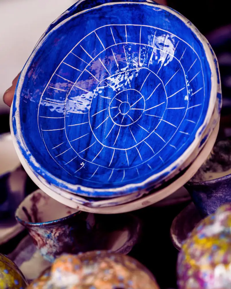 a blue bowl with white lines on it demonstrated cool pottery ideas by using crackle glaze