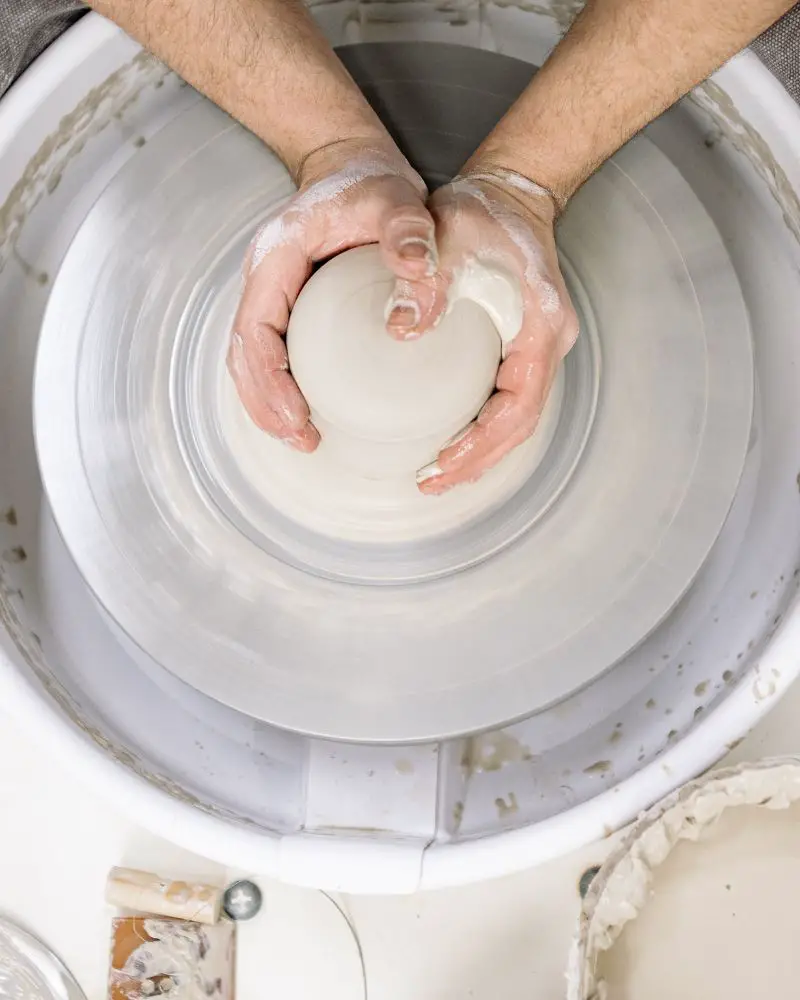 hands holding a bowl of clay using a technique known as hand-throwing