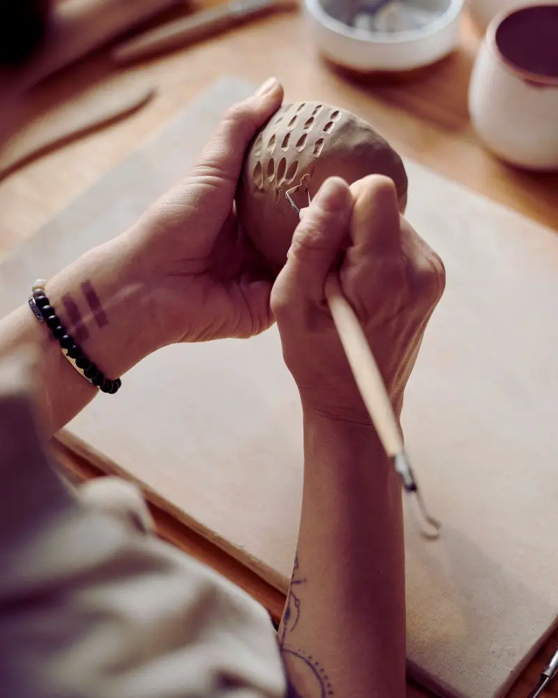 a person painting a clay object after discovering a few cool pottery ideas