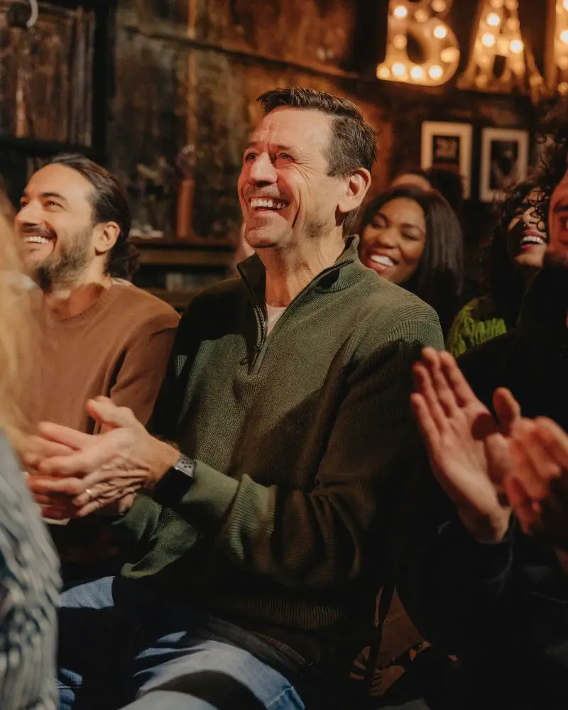 a group of people clapping and laughing at funny female comedians over 50