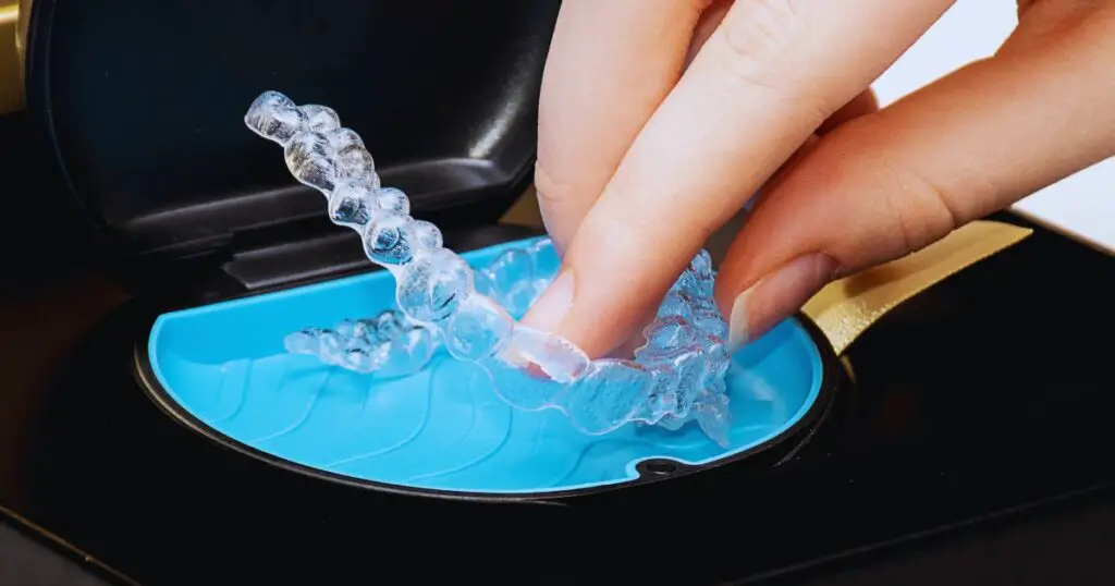 a hand holding a clear plastic retainer