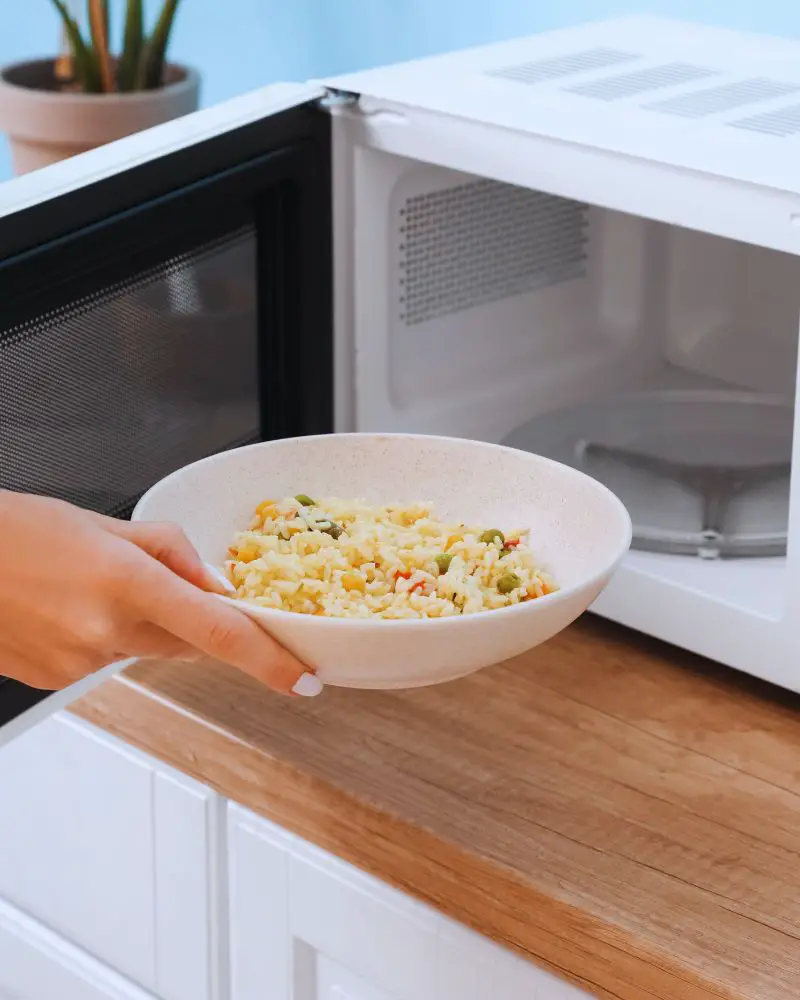 a hand holding a bowl of food to put into the microwave wondering is pottery  microwave safe?