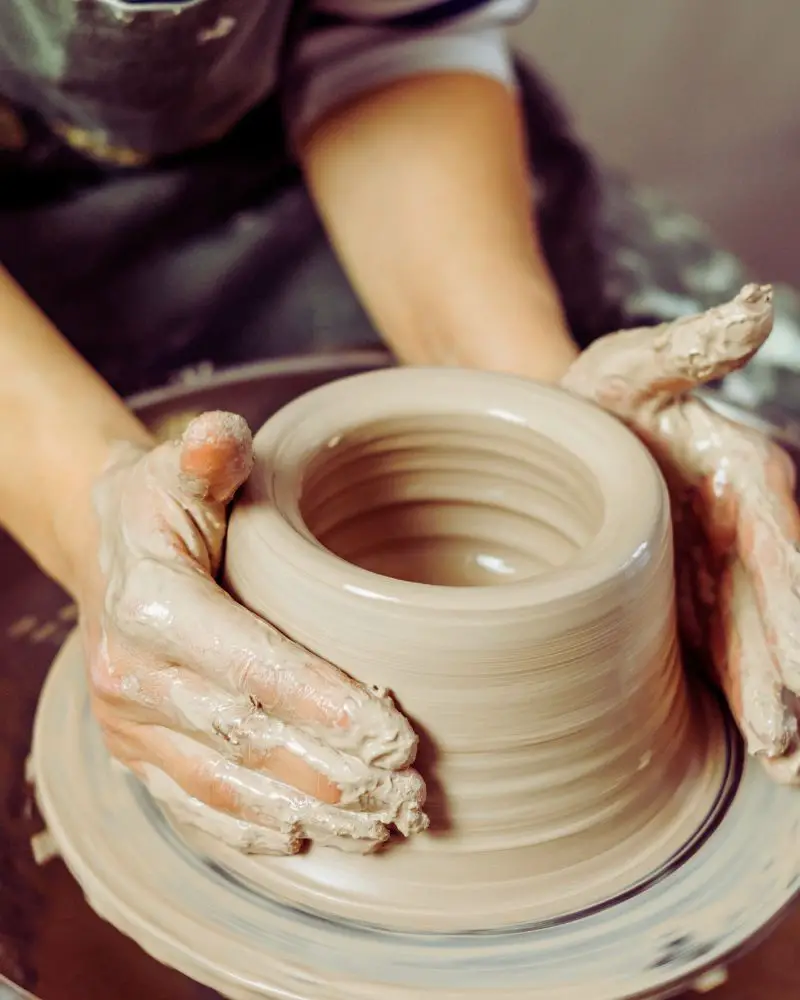 a person's hands making a clay pot that will be microwave safe