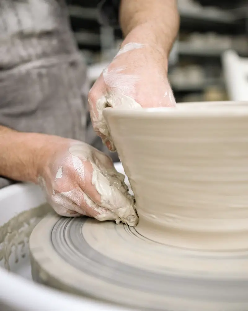 a person working on a pottery wheel using essential pottery studio supplies