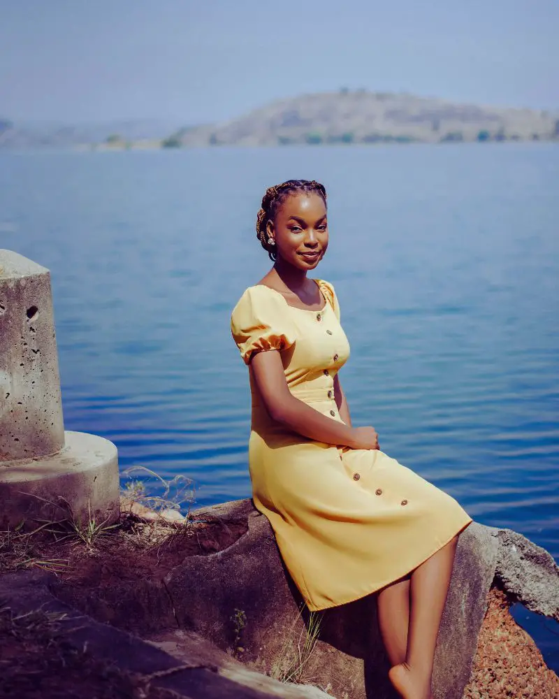 a woman sitting on a rock by water