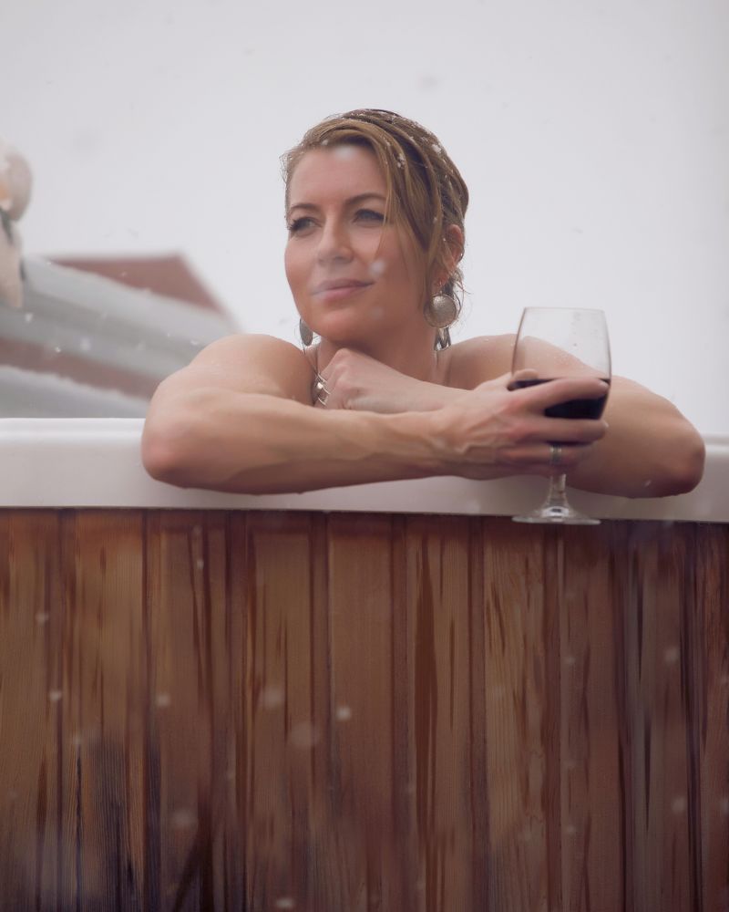 a woman holding a glass of wine in a hot tub after debating the pros and cons of getting a hot tub vs a pool