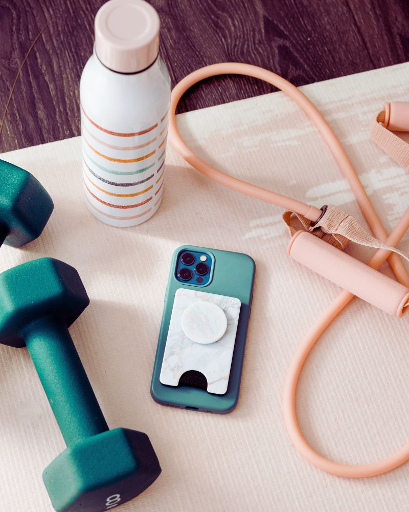 a phone and dumbbells on a mat demonstrating the best exercise equipment over 60