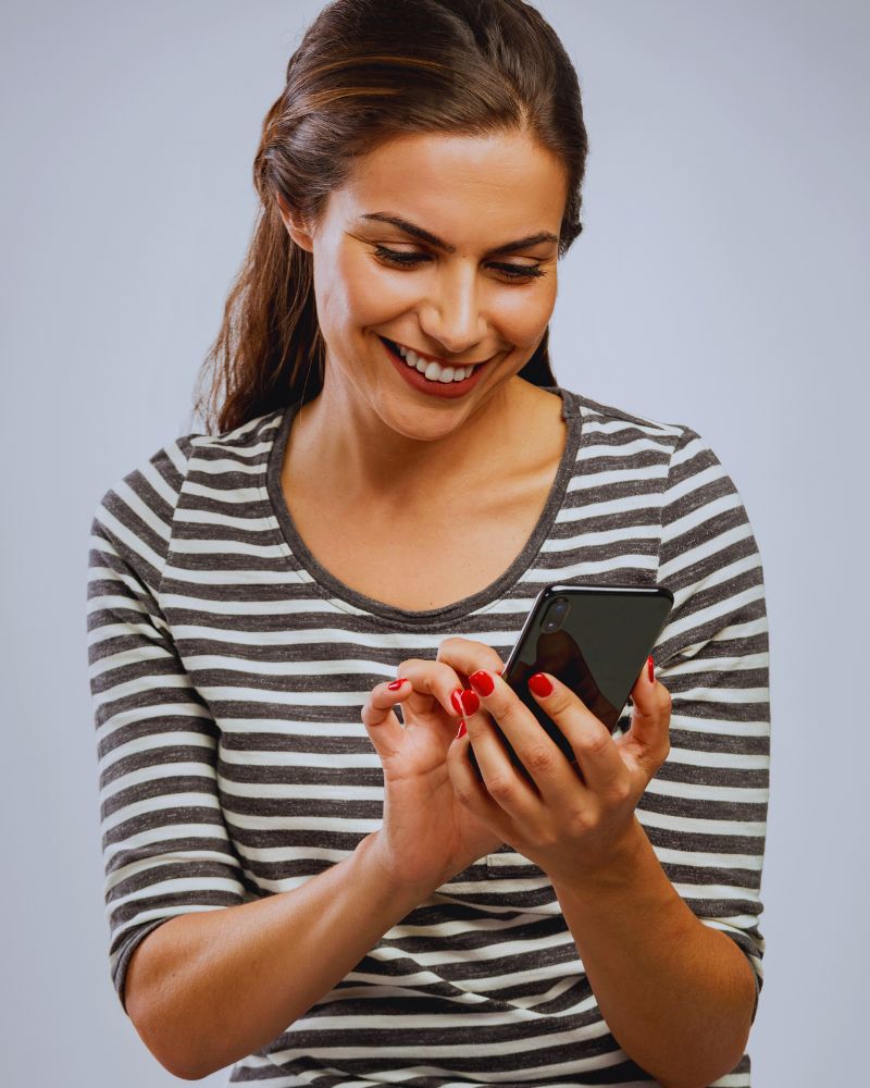 a woman smiling while looking at a cellphone while using an executive function planner for adults