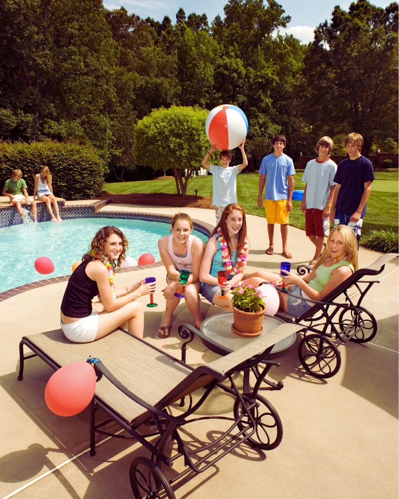 a group of people sitting around a pool after considering the differences between a swim spa vs a pool