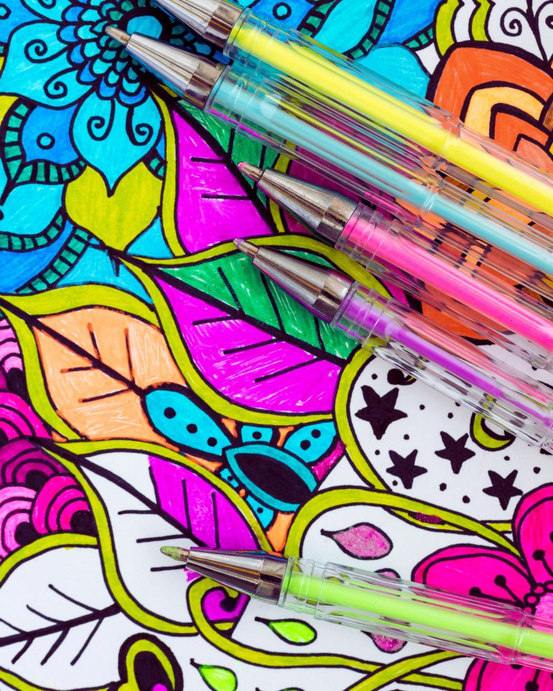 a group of pens on a colorful background to demonstrate adult geometric coloring pages