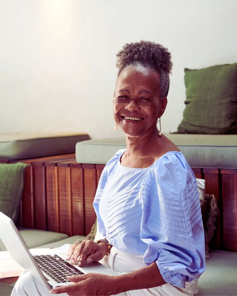 a woman smiling at a laptop because she is part of many people involved in senior side hustle statistics