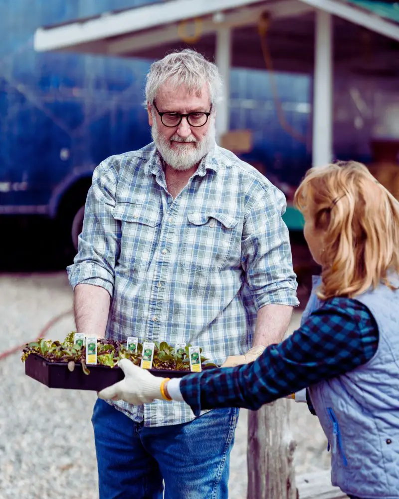 a man and woman holding a tray of plants