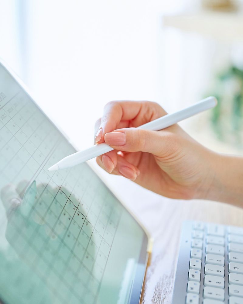 A hand holding a stylus using a planner for writers