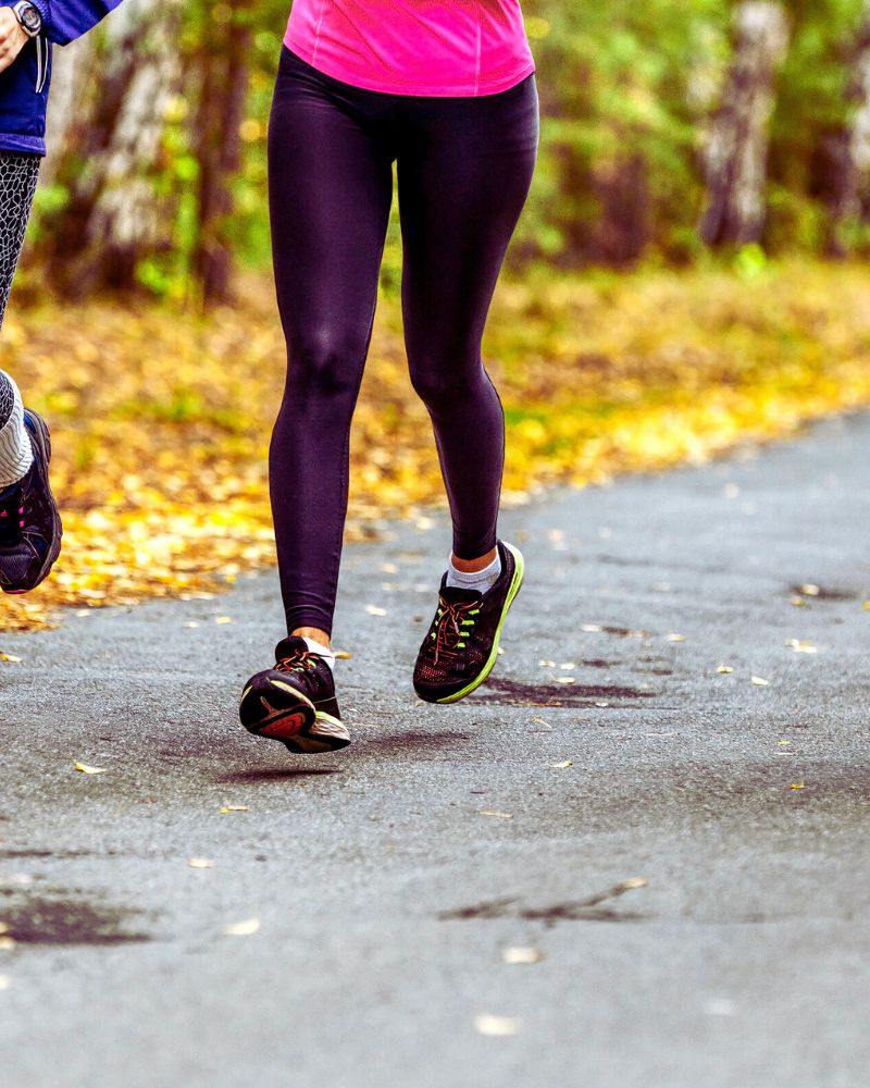 a person running on a road wearing leggings for women over 60