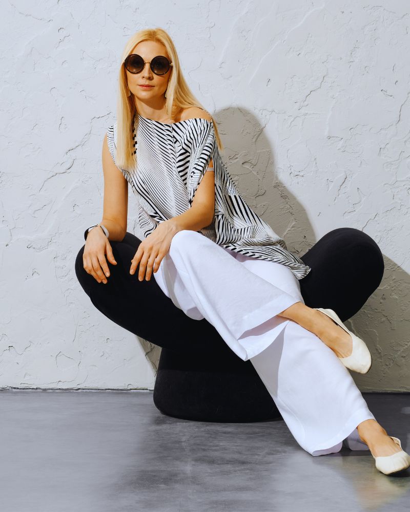 a woman sitting in a chair wearing wide leg pants over 50